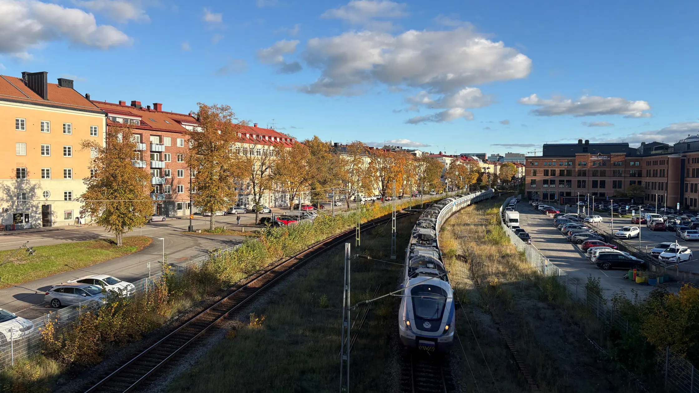 Pendeltåg på spåret genom Sundbybergs stadskärna en höstig dag.
