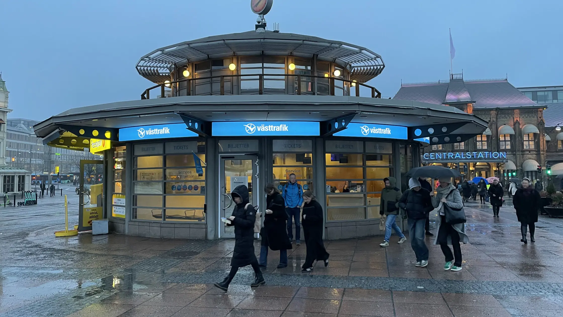 Drottningtorget människor hastar förbi Västtrafiks butik en regnig morgon.