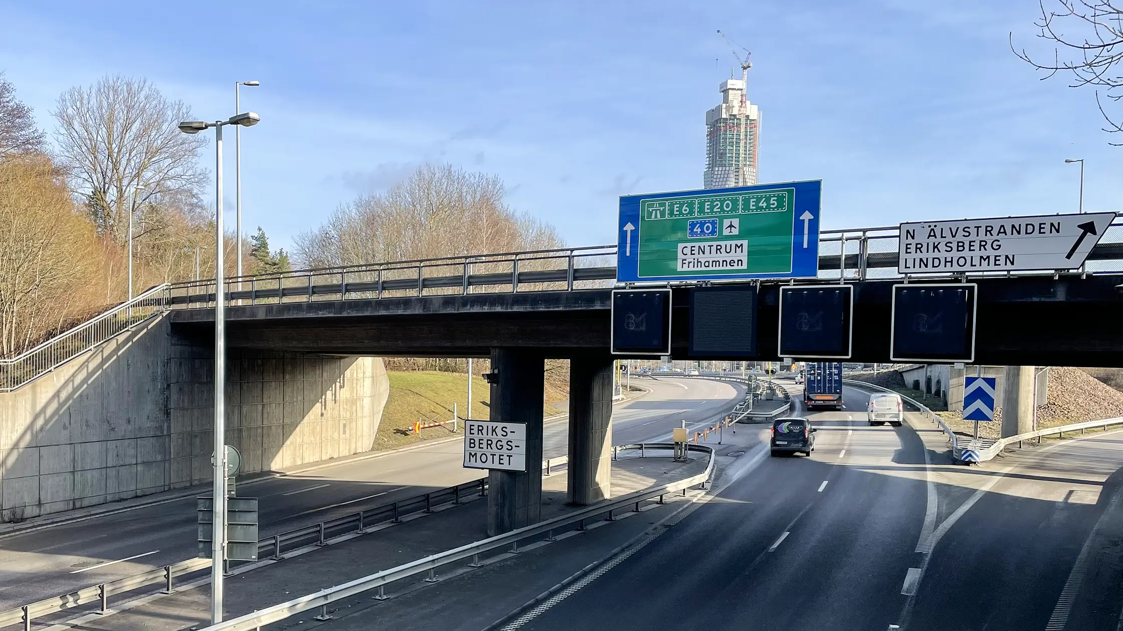 Vägskyltar på bron vid Eriksbergsmotet och Lundbyleden syns gå under bron. Karlatornet syns i bakgrunden.