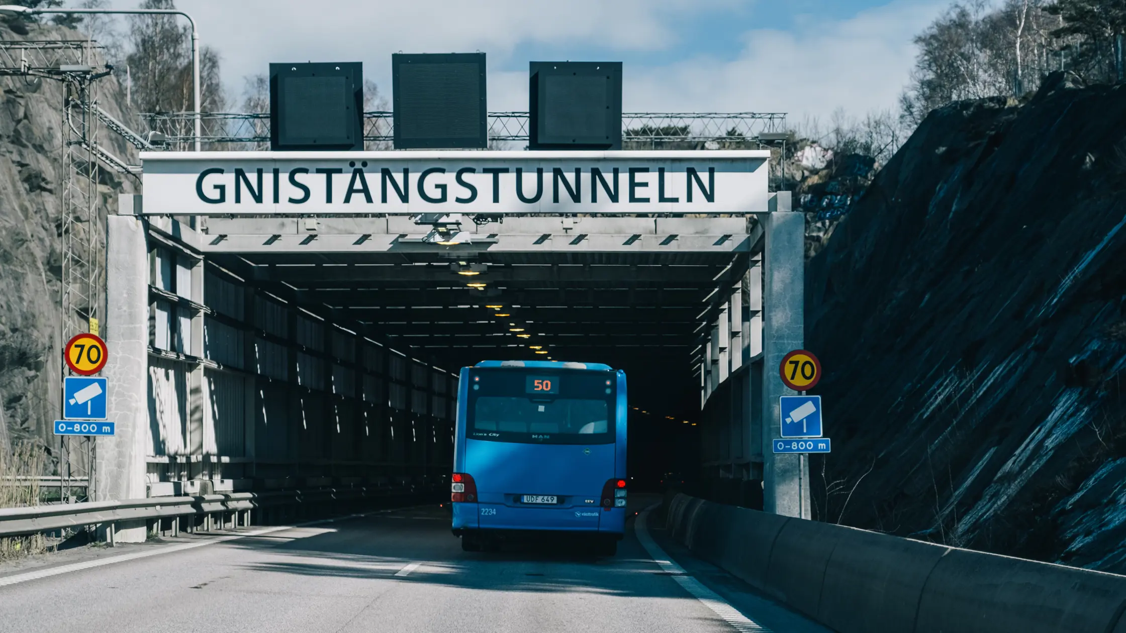 En buss kör in i Gnistängstunneln. Skylten med Gnistängstunneln syns över tunnelmynningen