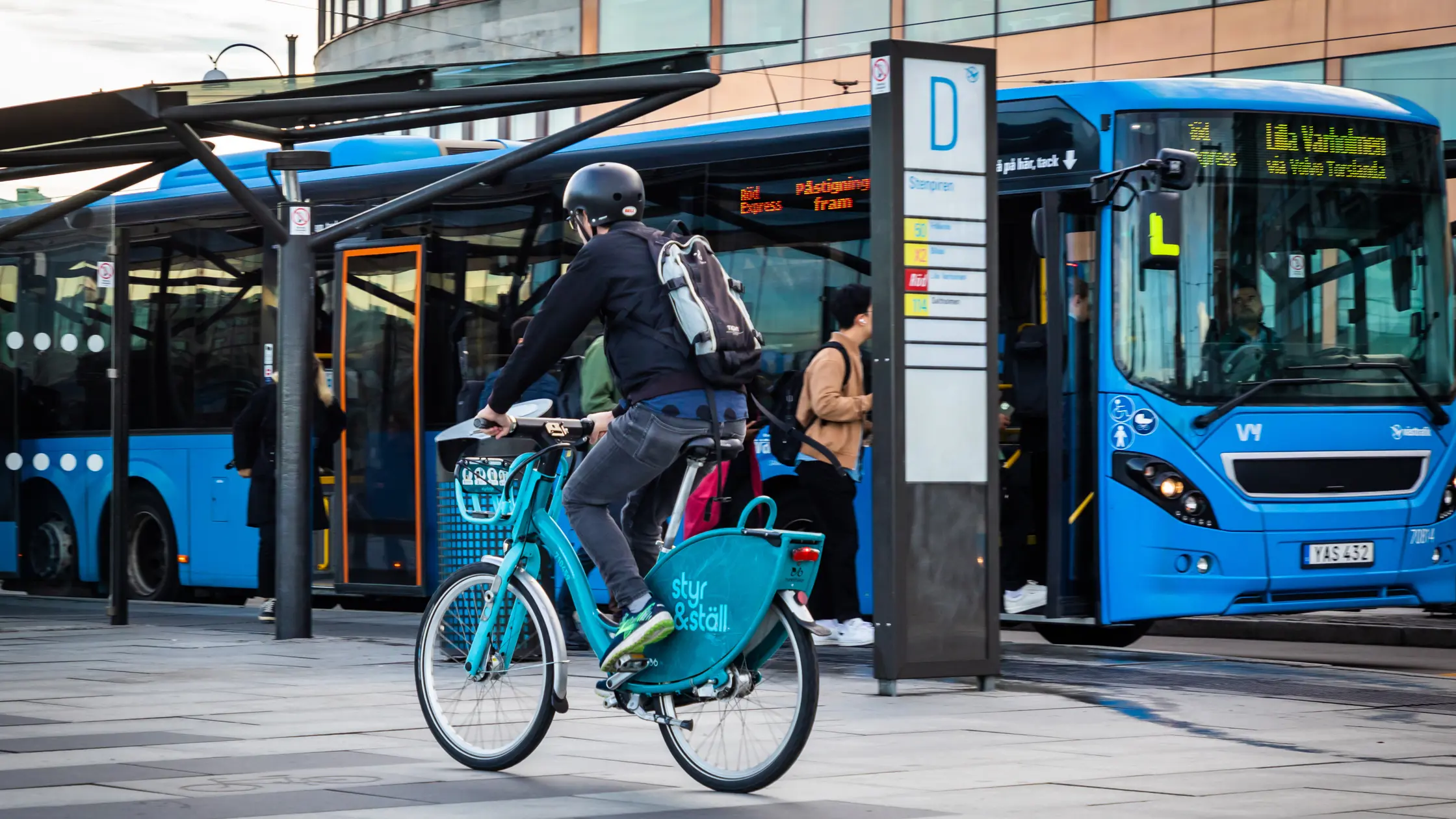 En cyklist på styr & ställ-cykel passerar en buss