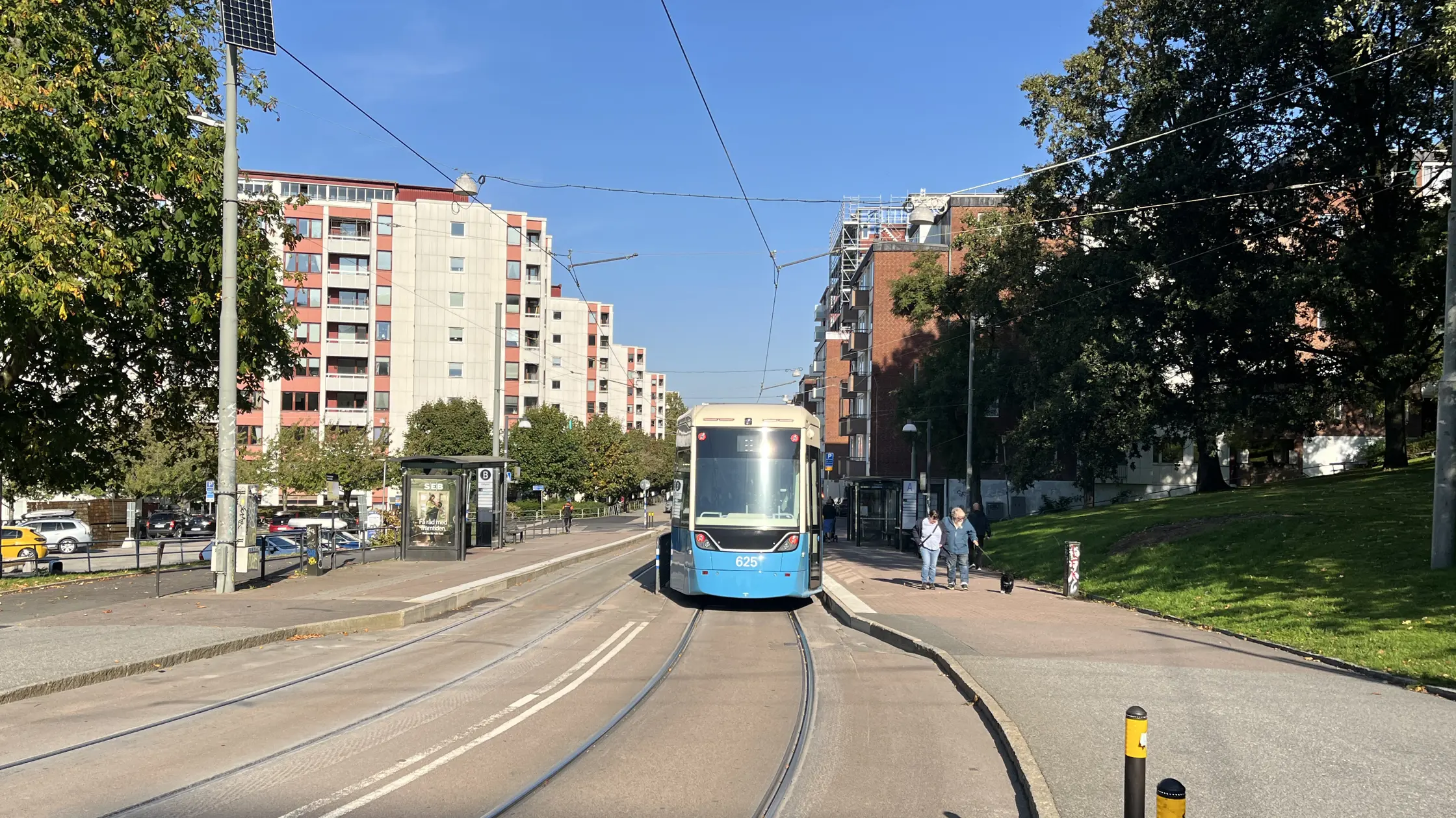 Spårvagn står still vid hållplatsen Fjällgatan och höga byggnader till vänster i bild syns.