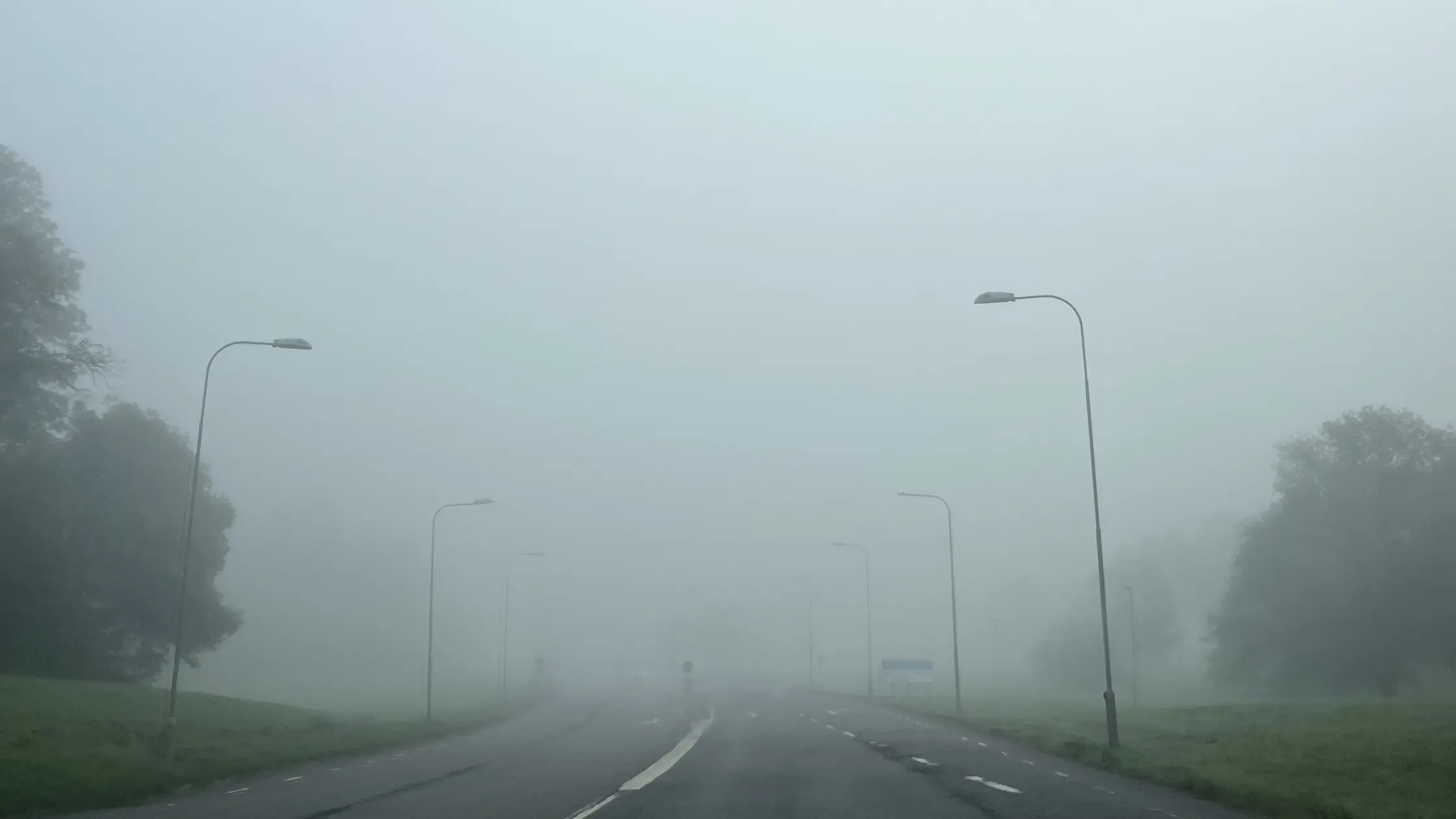 Dimma över Skälltorpsvägen på Hisingen lyktorna från en bil syns svagt i dimman.