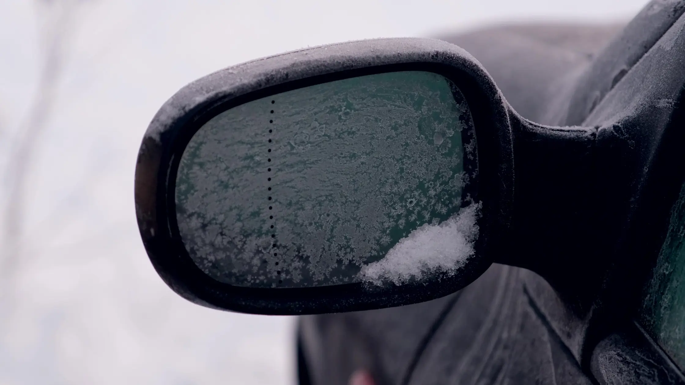Bilden visar en bilbackspegel med frost och små snökristaller.