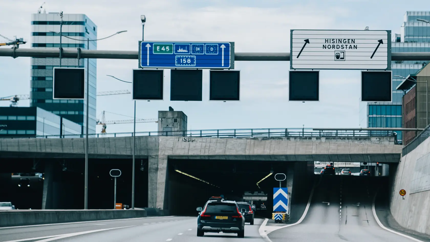 Personbilar syns köra in i Gullbergstunneln mot centrum. Läppstiftet och Regionens hus syns i bakgrunden.