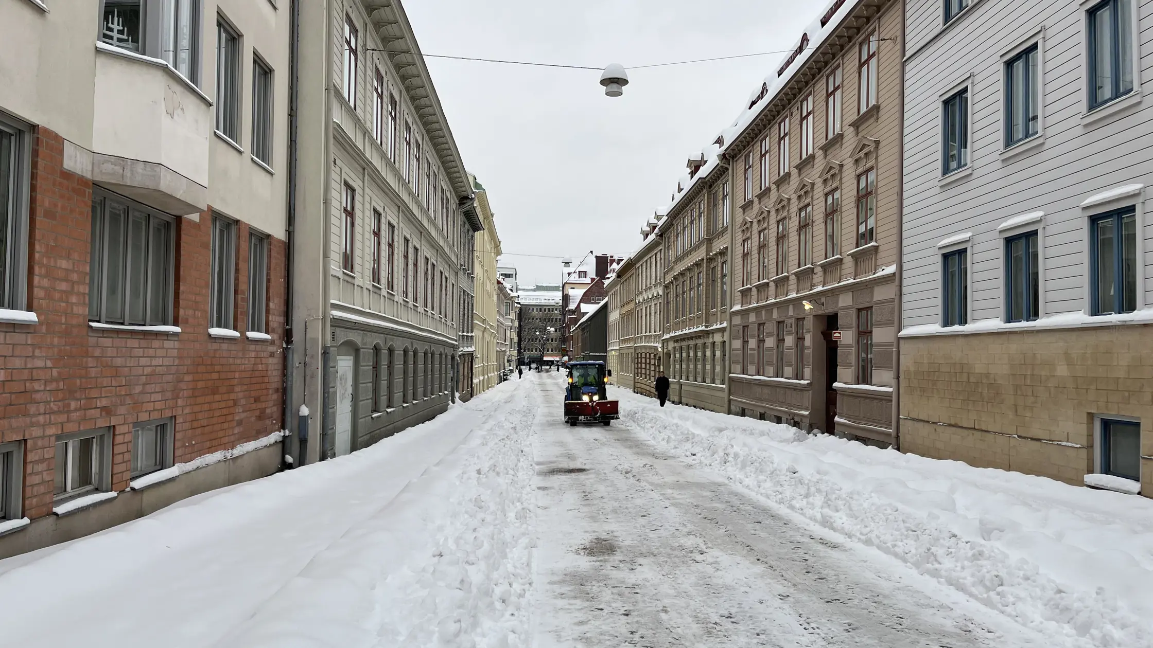 En plogbil kommer körande på en nyplogad bostadsgata i Haga mellan två stora snövallar.